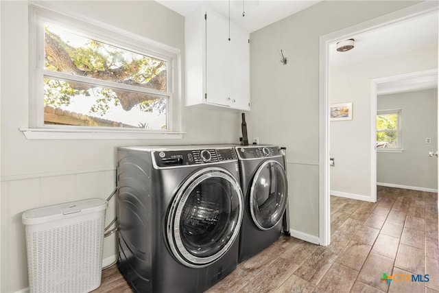 clothes washing area featuring cabinets, independent washer and dryer, and light hardwood / wood-style floors