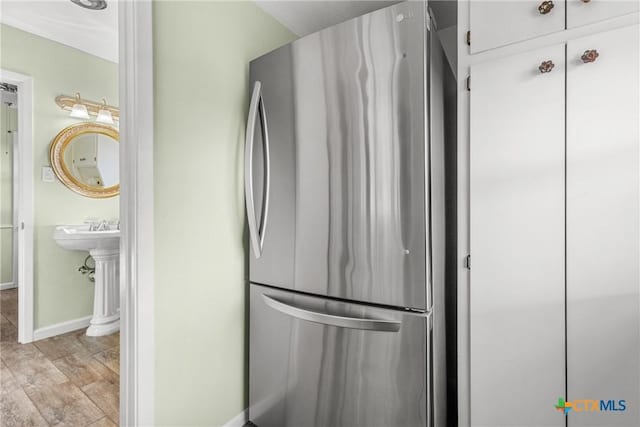 kitchen with stainless steel refrigerator, light hardwood / wood-style floors, and white cabinets