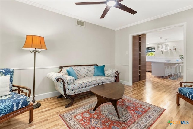 living area featuring crown molding, ceiling fan, and wood-type flooring