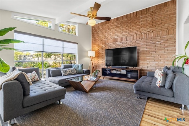 living room featuring ceiling fan, brick wall, hardwood / wood-style floors, and beam ceiling