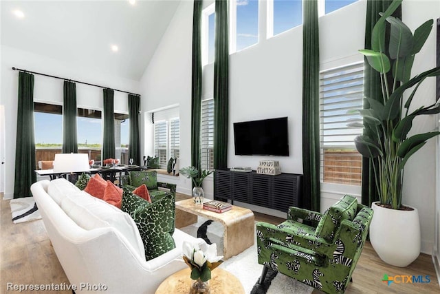 living room with a healthy amount of sunlight, light wood-type flooring, and high vaulted ceiling