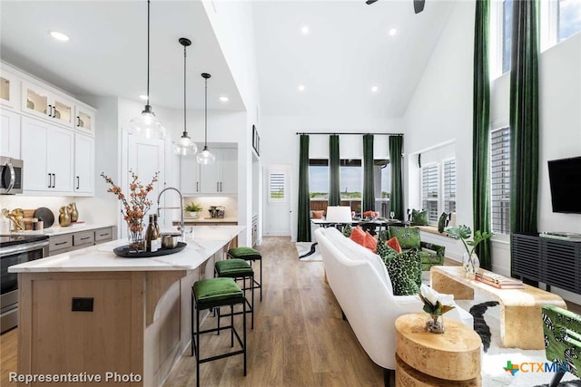 kitchen featuring decorative light fixtures, a spacious island, white cabinetry, and appliances with stainless steel finishes