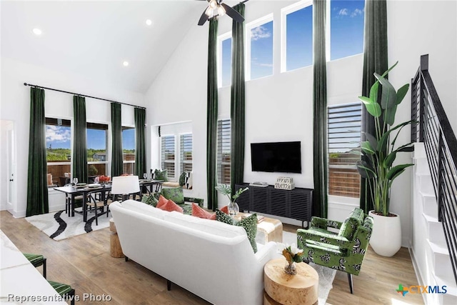 living room featuring ceiling fan, high vaulted ceiling, and light hardwood / wood-style flooring