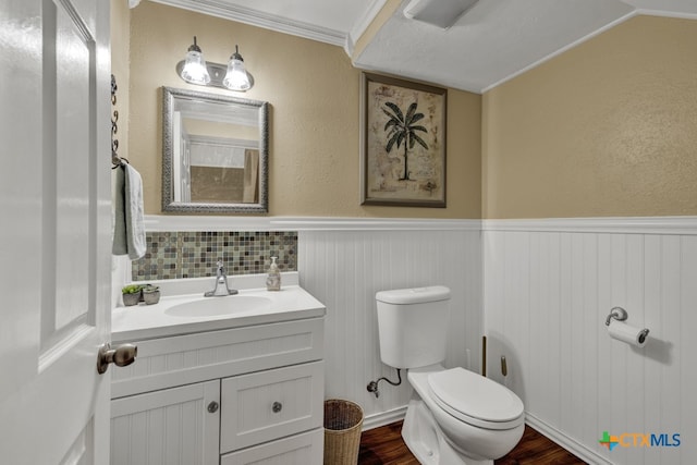 bathroom with ornamental molding, tasteful backsplash, wood-type flooring, vanity, and toilet