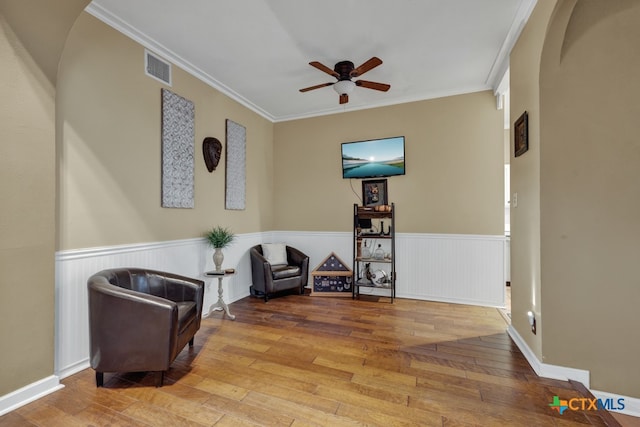 living area featuring light wood-type flooring, ceiling fan, and crown molding