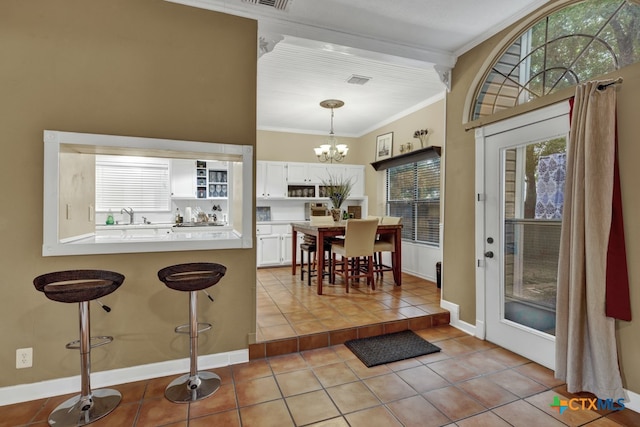 kitchen with crown molding, white cabinetry, decorative light fixtures, light tile patterned floors, and a chandelier