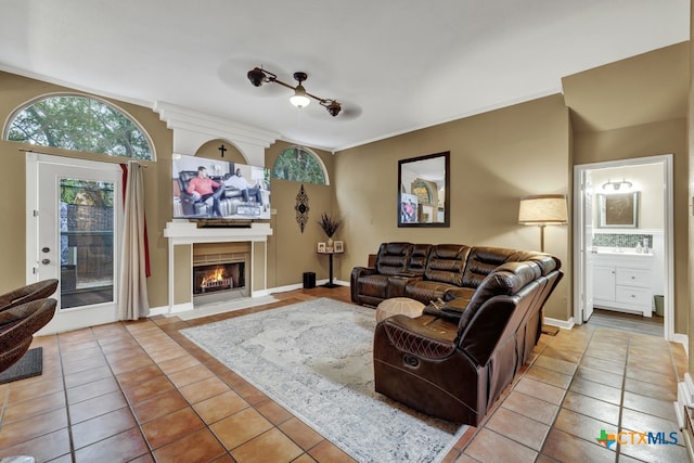 tiled living room featuring a fireplace, ceiling fan, and crown molding