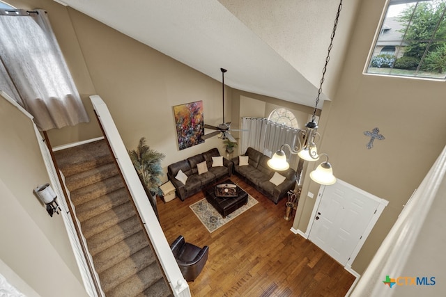 stairs with a textured ceiling, high vaulted ceiling, hardwood / wood-style flooring, and ceiling fan