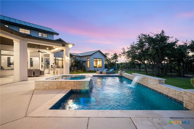 pool at dusk featuring a ceiling fan, an outdoor pool, a patio, and an in ground hot tub