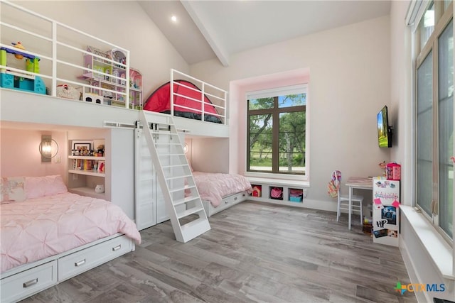 bedroom with vaulted ceiling with beams and wood finished floors