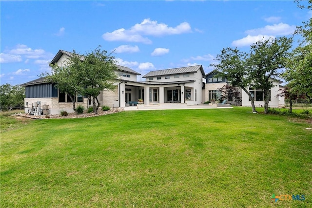 rear view of house featuring a patio area and a lawn