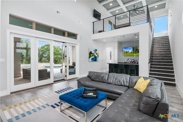 living room with a dry bar, visible vents, baseboards, wood finished floors, and stairs