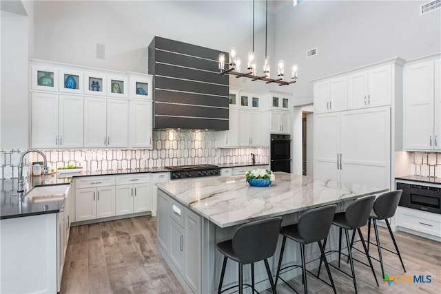 kitchen with visible vents, white cabinets, a sink, a kitchen island, and range