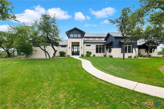 view of front facade featuring stone siding, a standing seam roof, metal roof, and a front lawn