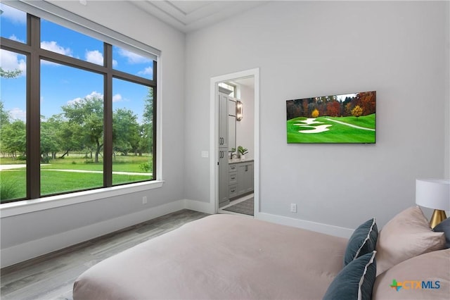 bedroom featuring connected bathroom, baseboards, and wood finished floors