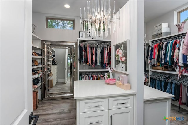 spacious closet with wood finished floors and a notable chandelier