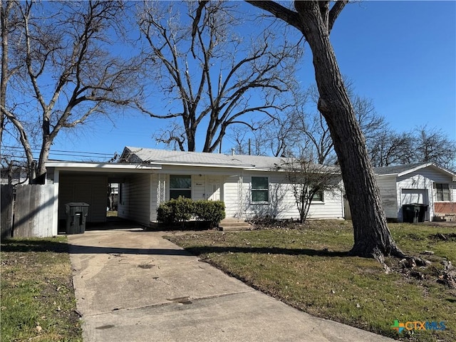 ranch-style home featuring driveway, an attached carport, and a front yard