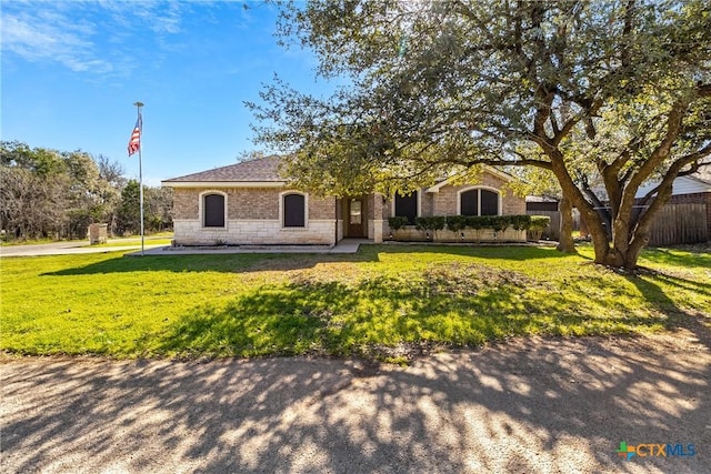 view of front of home featuring stone siding, a front yard, and fence