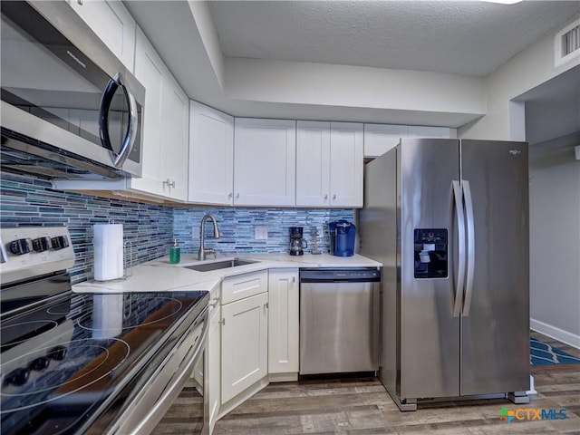 6021 State Highway 361 Unit 108, Port Aransas, TX 78373 - kitchen featuring appliances with stainless steel finishes, a sink, light wood finished floors, white cabinets, and backsplash