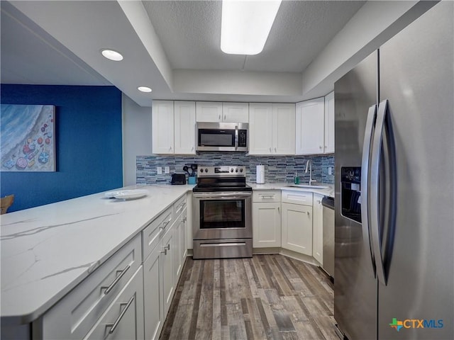 6021 State Highway 361 Unit 108, Port Aransas, TX 78373 - kitchen featuring stainless steel appliances, a sink, wood finished floors, tasteful backsplash, and white cabinetry