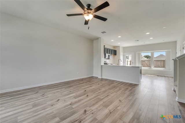 unfurnished living room with ceiling fan, light hardwood / wood-style flooring, and sink