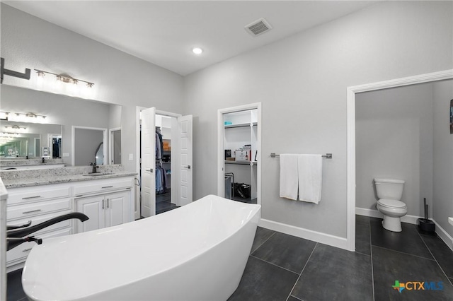 bathroom with vanity, a tub to relax in, tile patterned floors, and toilet