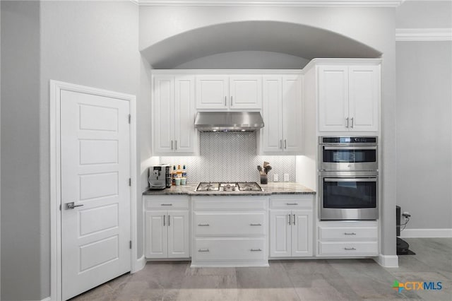 kitchen with light stone countertops, decorative backsplash, stainless steel appliances, and white cabinets