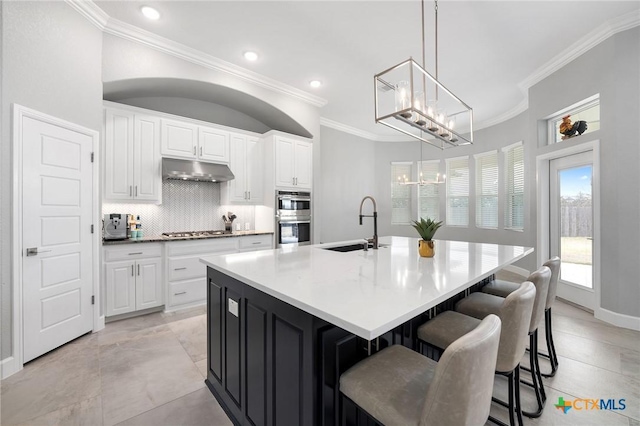 kitchen with pendant lighting, sink, appliances with stainless steel finishes, a spacious island, and white cabinets