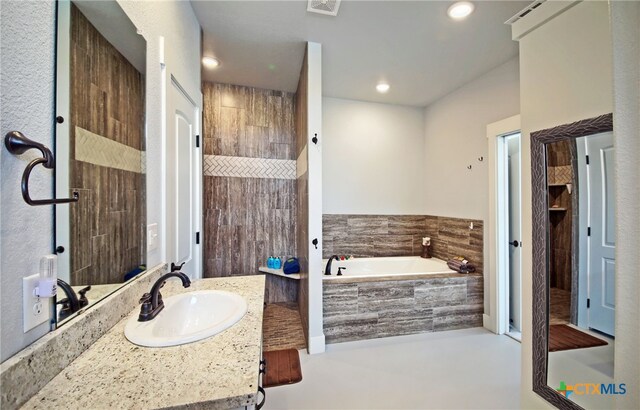 bathroom featuring shower with separate bathtub and vanity