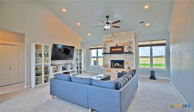 carpeted living room with high vaulted ceiling, ceiling fan, and a stone fireplace