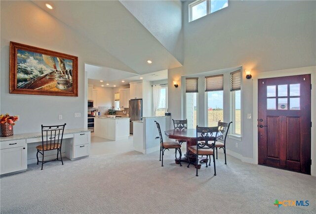 carpeted dining area with plenty of natural light and high vaulted ceiling