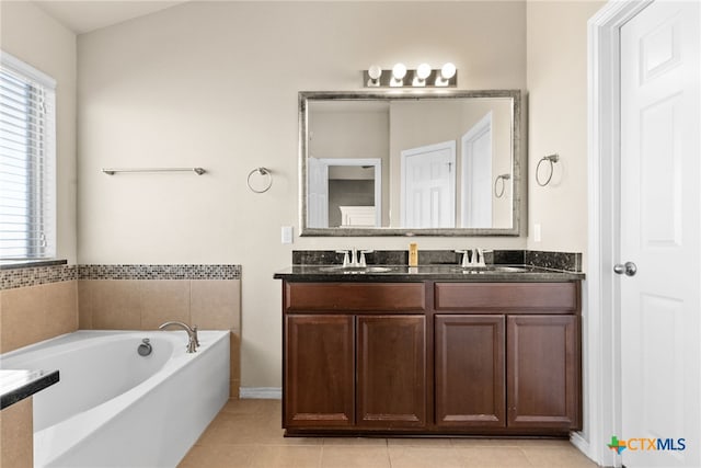 bathroom with a washtub, tile patterned floors, and vanity