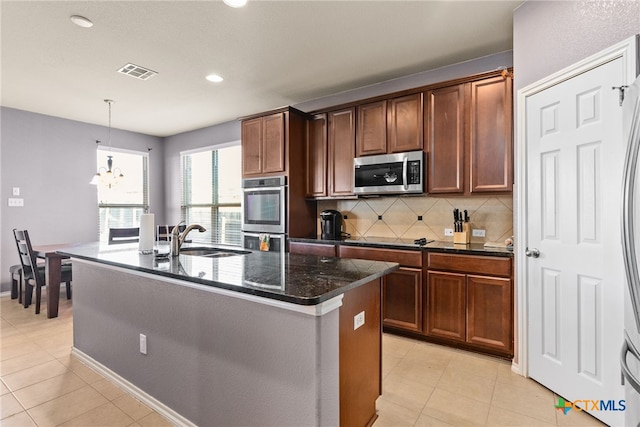 kitchen featuring pendant lighting, sink, an inviting chandelier, appliances with stainless steel finishes, and an island with sink