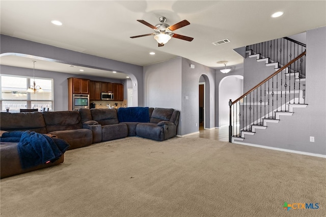 living room with ceiling fan with notable chandelier and light carpet