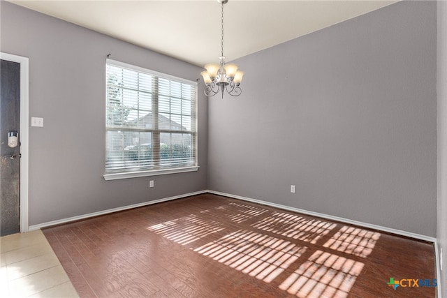 empty room with dark wood-type flooring and a chandelier