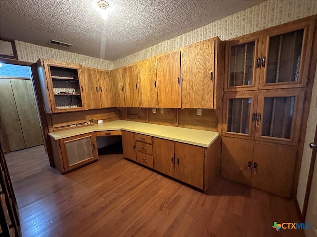 kitchen featuring built in desk, wood-type flooring, and a textured ceiling