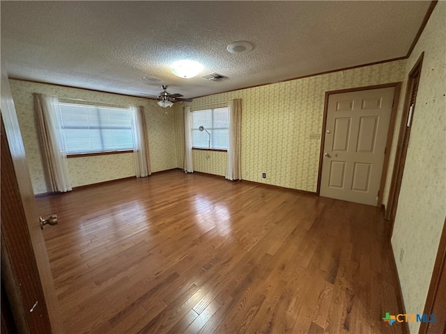 unfurnished bedroom featuring wood-type flooring, a textured ceiling, and crown molding