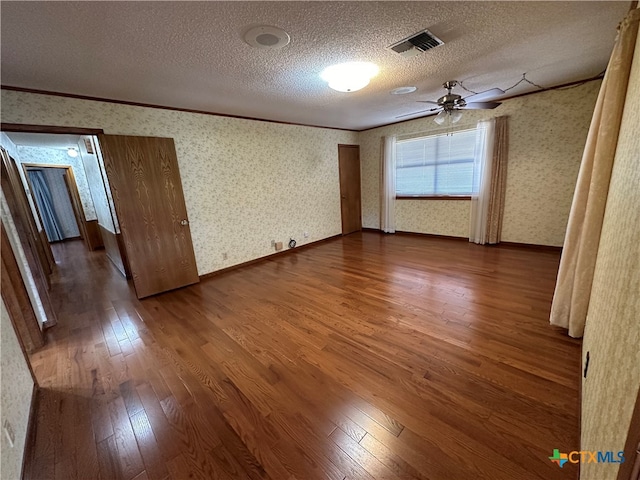 empty room featuring crown molding, wood-type flooring, ceiling fan, and a textured ceiling