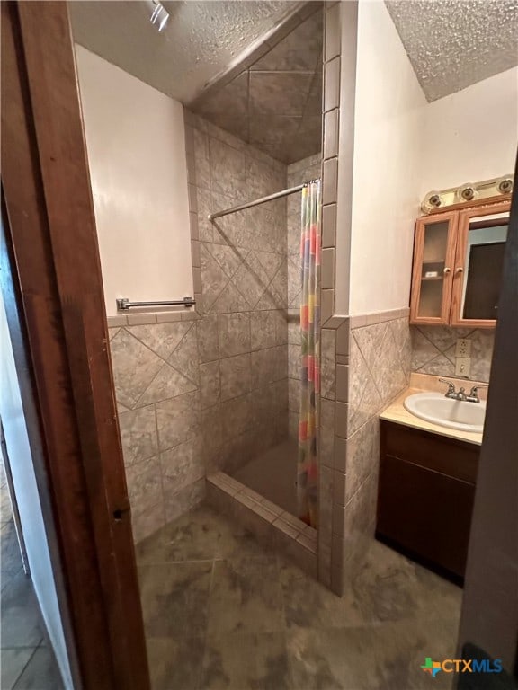 bathroom with vanity, a shower with curtain, tile walls, and a textured ceiling