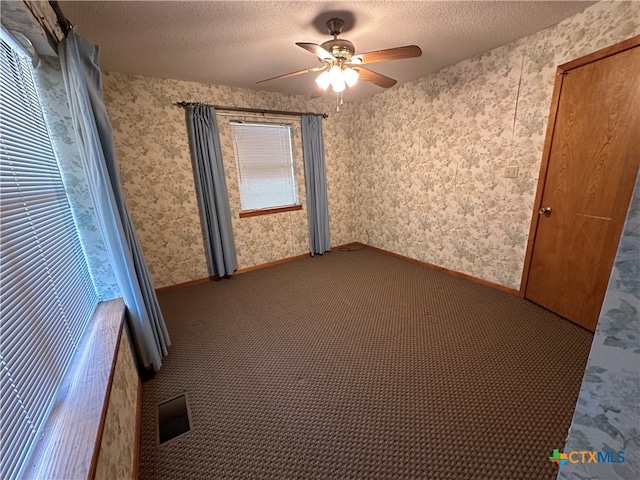 carpeted spare room featuring ceiling fan and a textured ceiling