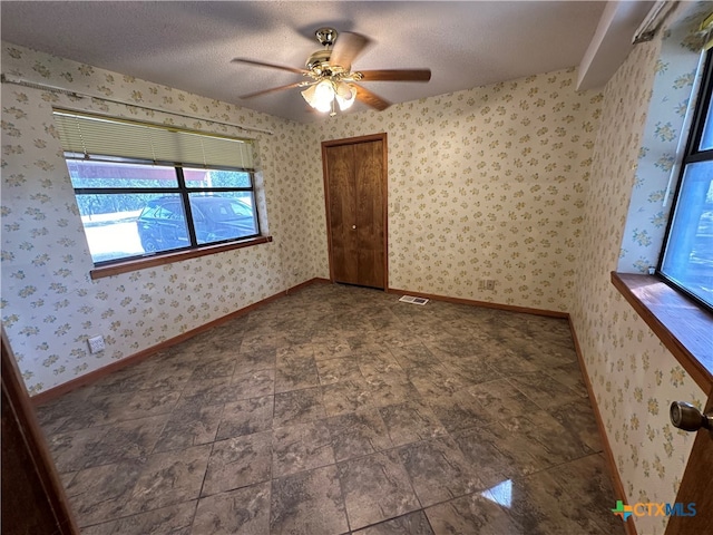 spare room with a textured ceiling and ceiling fan