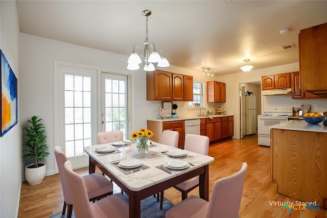 dining area with light wood-style floors, plenty of natural light, visible vents, and a chandelier