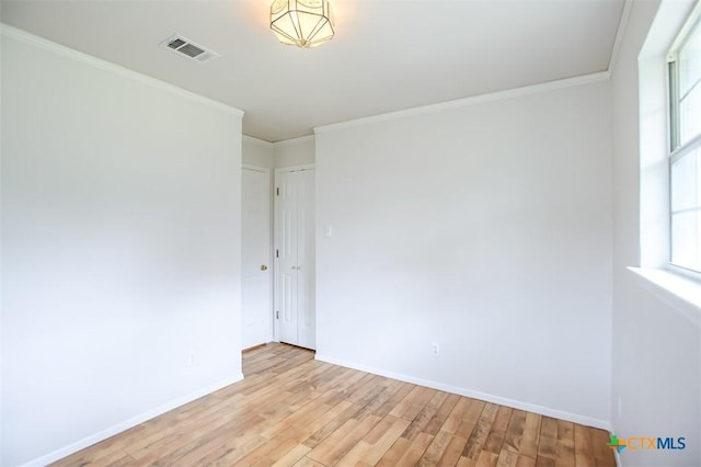 empty room with crown molding, baseboards, visible vents, and light wood-style floors