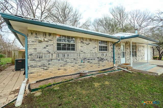 single story home featuring a garage, concrete driveway, metal roof, cooling unit, and brick siding