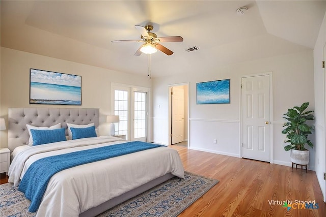 bedroom with ceiling fan, visible vents, baseboards, vaulted ceiling, and light wood-style floors