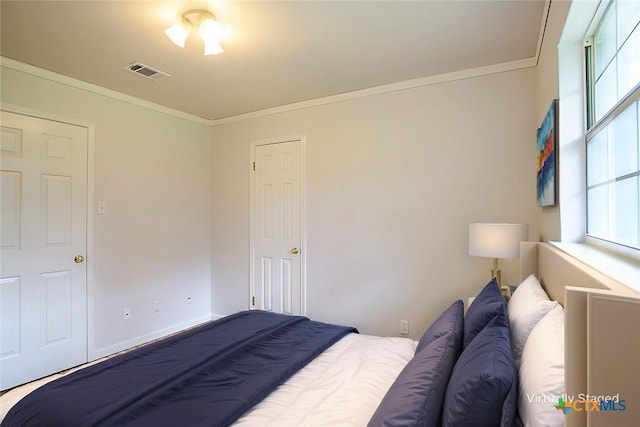 bedroom with baseboards, multiple windows, visible vents, and crown molding