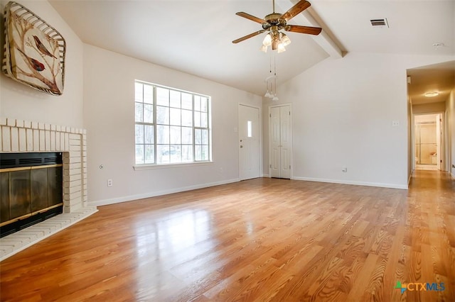 unfurnished living room featuring lofted ceiling with beams, light wood finished floors, a fireplace, and visible vents