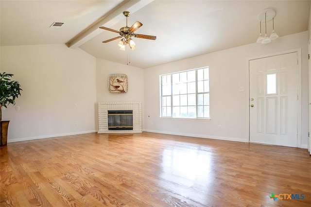 unfurnished living room featuring a fireplace, lofted ceiling with beams, ceiling fan, light wood-type flooring, and baseboards