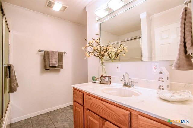 bathroom featuring visible vents, a shower with shower door, vanity, baseboards, and tile patterned floors