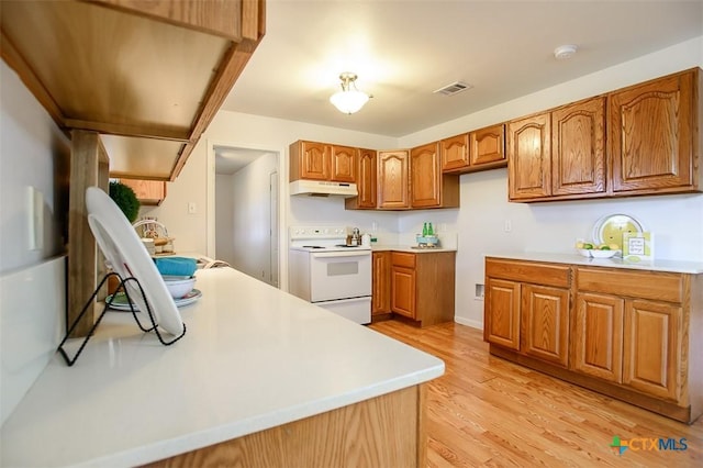 kitchen with light wood finished floors, visible vents, electric stove, brown cabinets, and under cabinet range hood